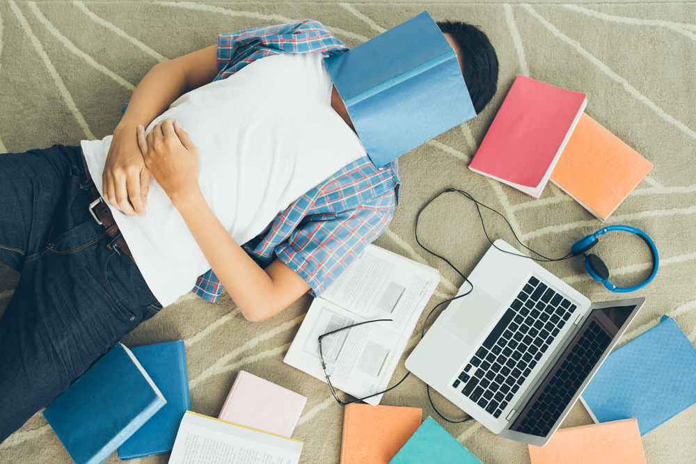 estudiante dormido con cuarernos en la cara