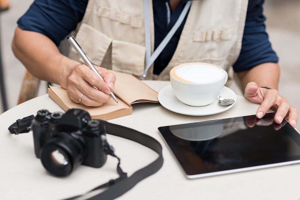 periodista anotando tomando un cafe