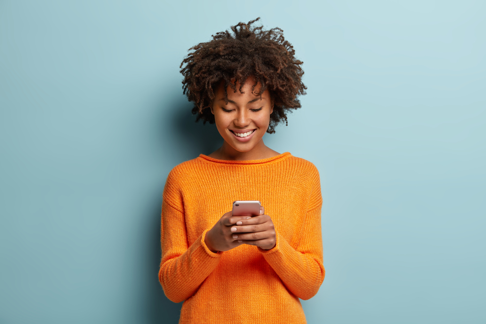 mujer sosteniendo celular sonriendo